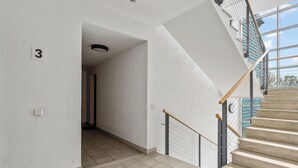 A modern interior with a staircase, tiled flooring, and a visible door with the number 3.