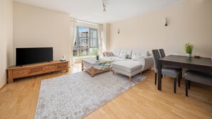 A modern living room with a flat-screen TV, a sofa, a dining table, and a coffee table.