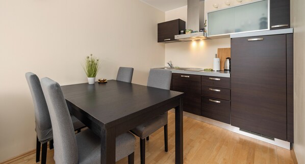 A modern kitchen with dark cabinetry, a wooden dining table, and grey chairs.