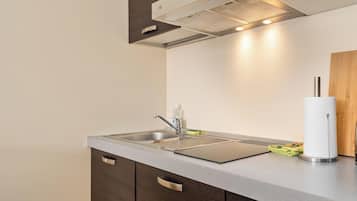 Een moderne keuken met een roestvrijstalen spoelbak, houten keukenkastjes en een inbouwafzuigkap.