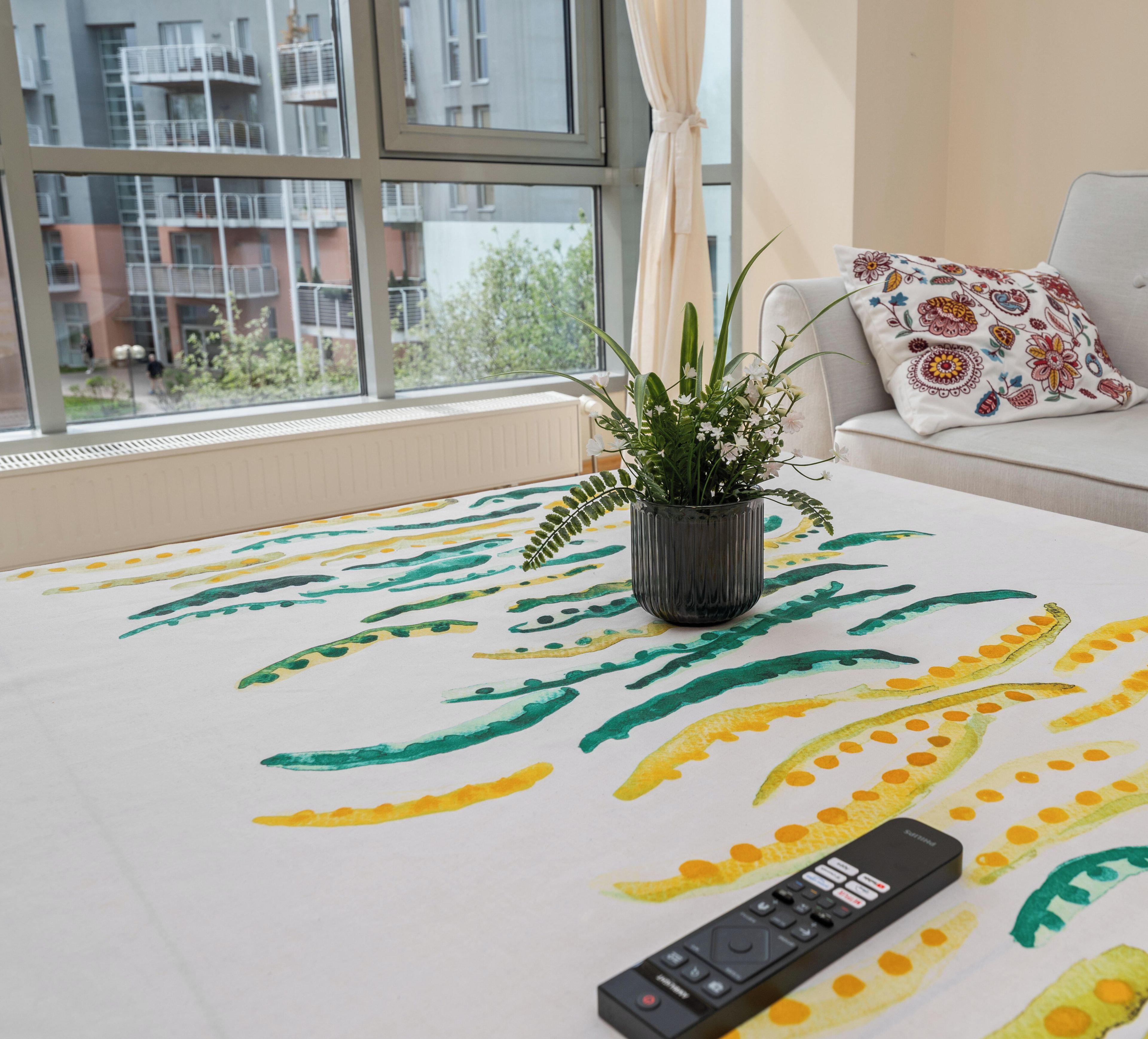 Un salon avec un canapé, une tél écommande et une plante posée sur une table.