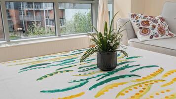 A living room with a sofa, a remote control, and a plant on a table.