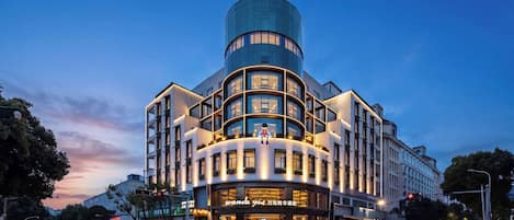 Un hôtel moderne doté d’une structure supérieure cylindrique originale, de plusieurs étages et d’une entrée imposante avec une enseigne lumineuse.