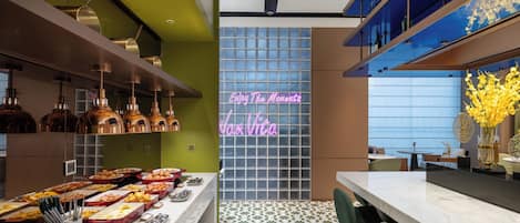 A modern restaurant interior with a buffet, neon sign, and a patterned floor.