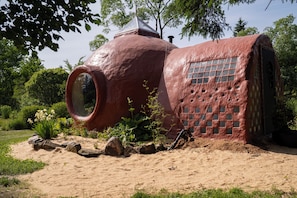 A unique building with a large circular window, a brick facade, and a natural surrounding.