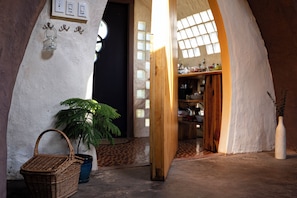 A cozy interior with a wooden door, a basket, a potted plant, and a shelf with various items.