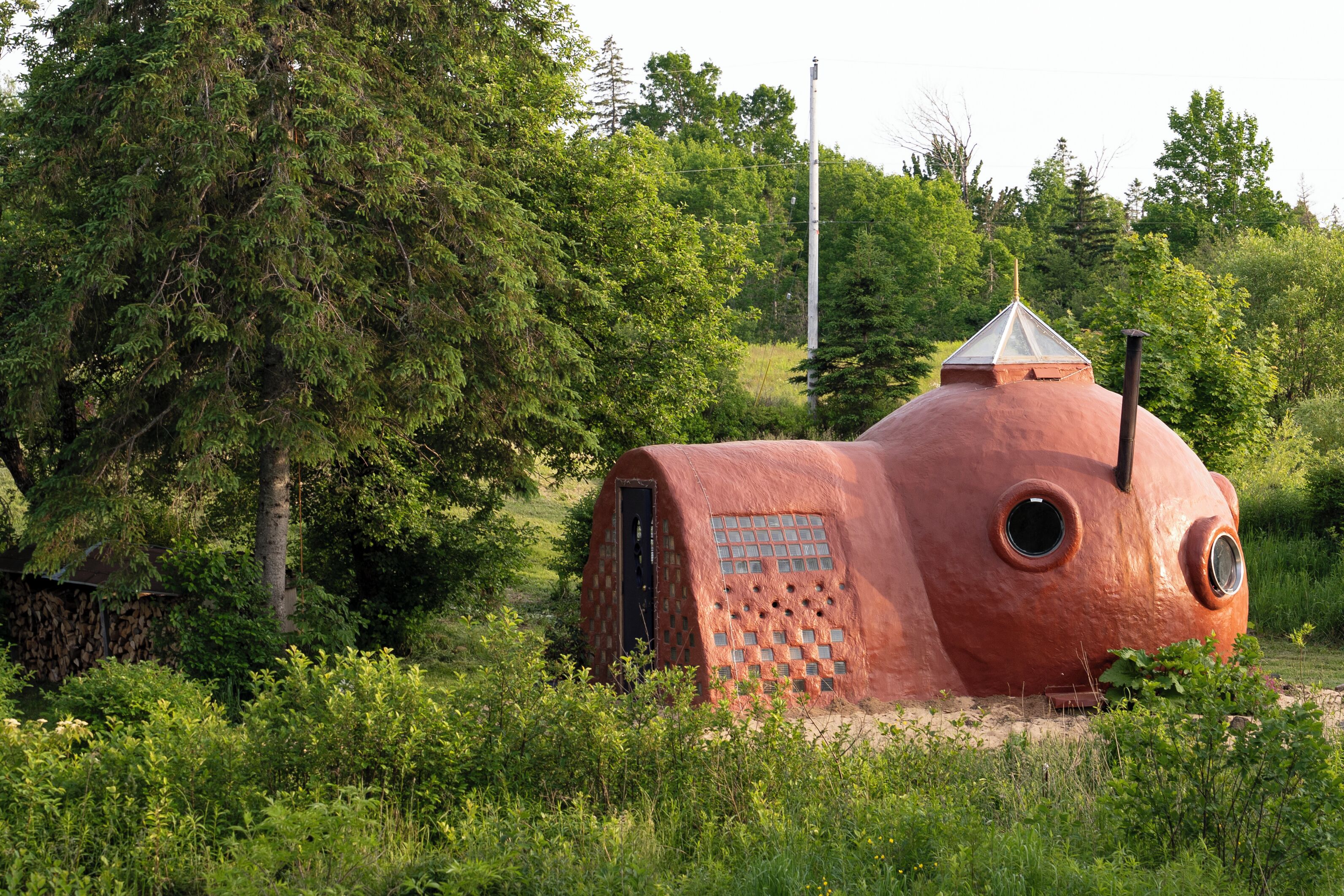 A unique, dome-shaped structure with a chimney, surrounded by lush greenery.