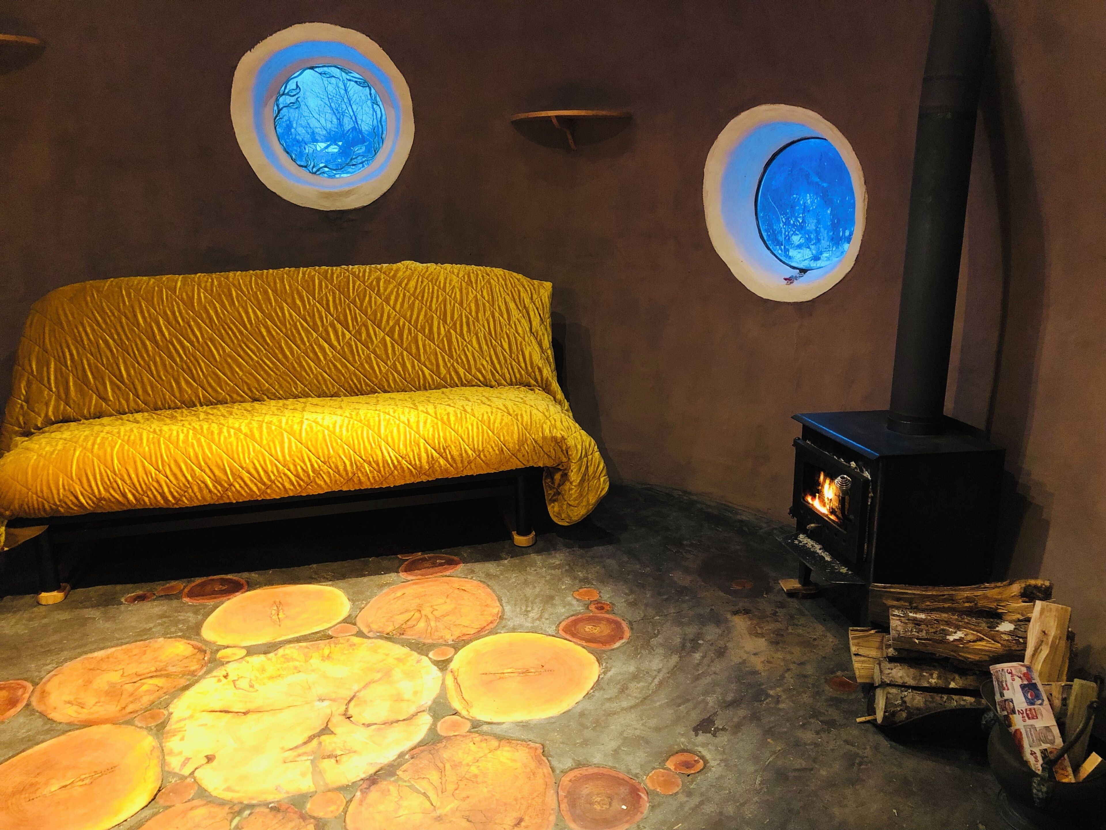 A room with a bed, a fireplace, and circular windows.