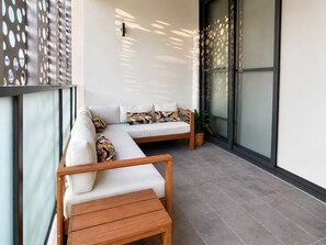 A balcony with a sofa, pillows, a wooden table, and a potted plant. - Modern 2BDR Retreat walk to Metro and Macquarie (Macquarie Park)