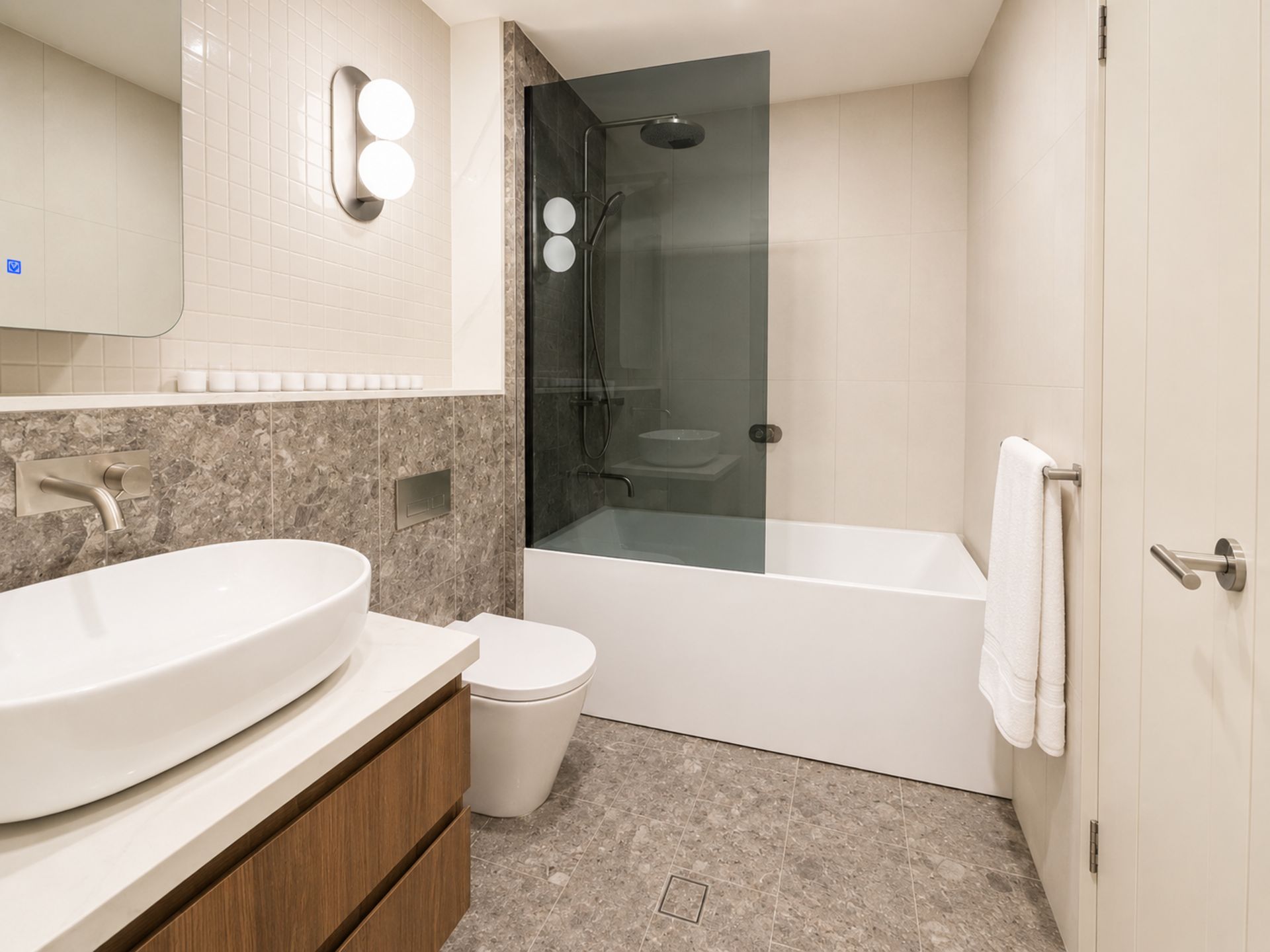 A modern bathroom with a large white sink, a toilet, and a glass-enclosed shower.