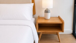 Un letto con biancheria bianca e un comodino con una lampada.