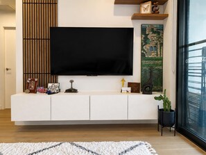 A modern living room with a large flat-screen TV mounted on a white cabinet, a wooden slat wall, and a decorative painting. - Modern 2BDR Retreat walk to Metro and Macquarie (Macquarie Park)