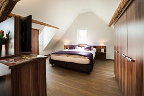 A bedroom with a bed, bedside tables, a wooden wardrobe, a window, and a sloped ceiling. - Gasthof zum Hecht Fehraltorf (Fehraltorf)