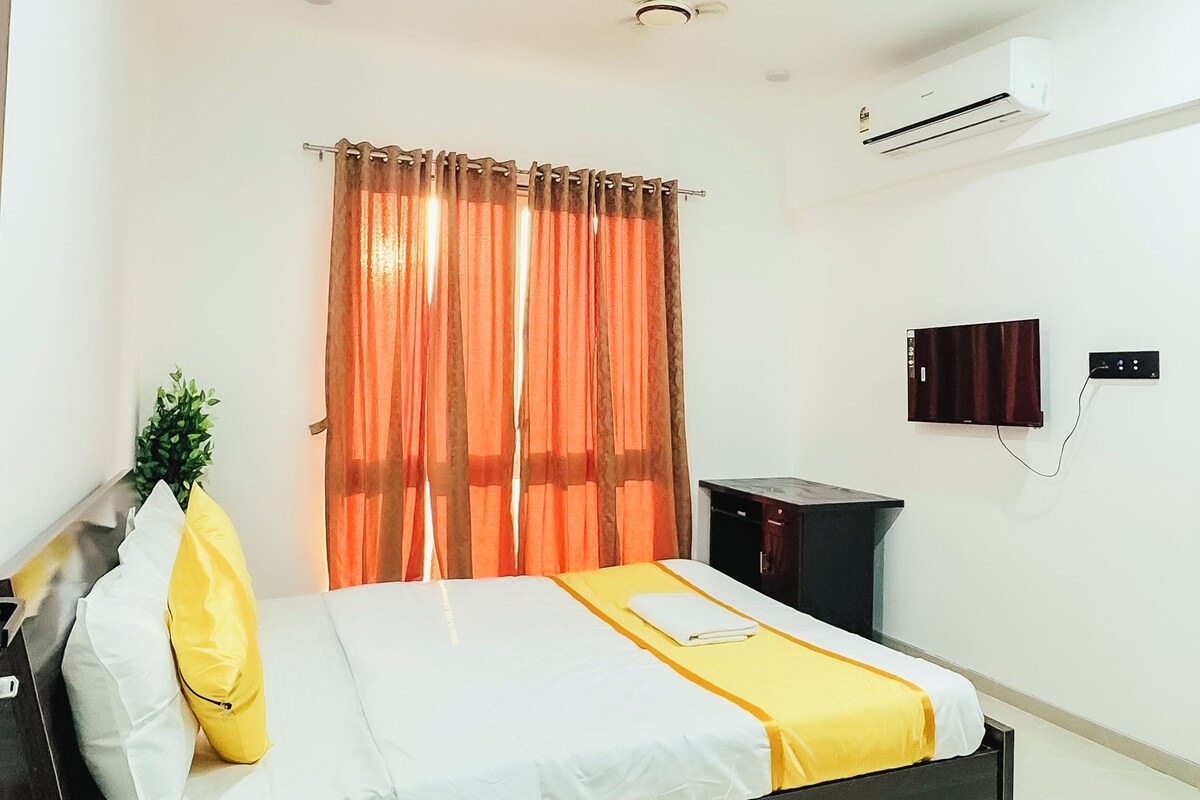 A hotel room with a bed, a TV, an air conditioning unit, and a ceiling fan.