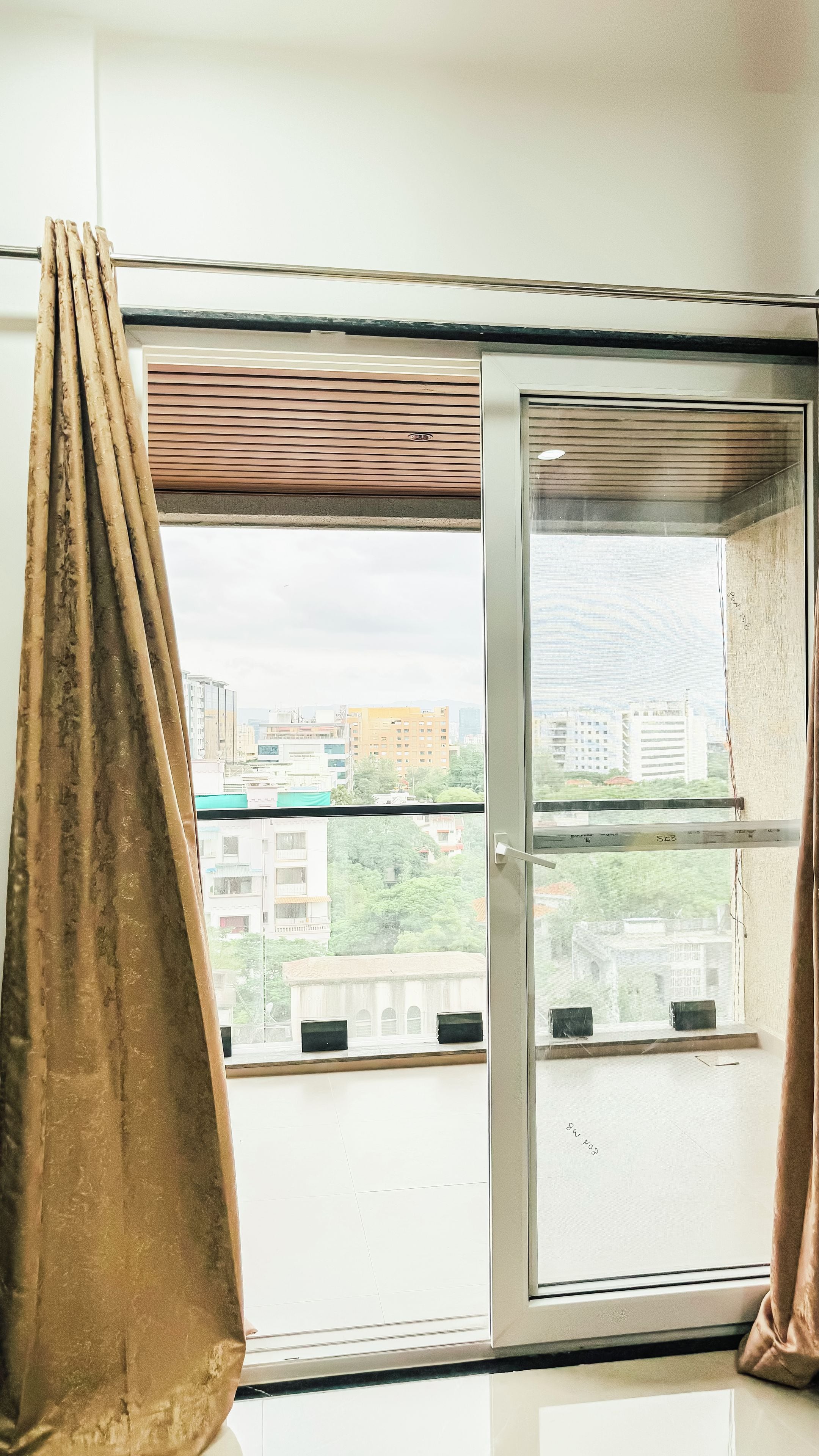 Una habitación con ventana, cortinas y vistas a edificios.