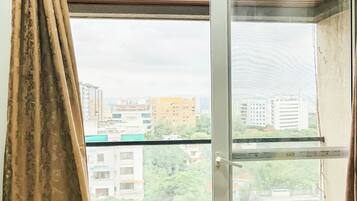 Una habitación con ventana, cortinas y vistas a edificios.