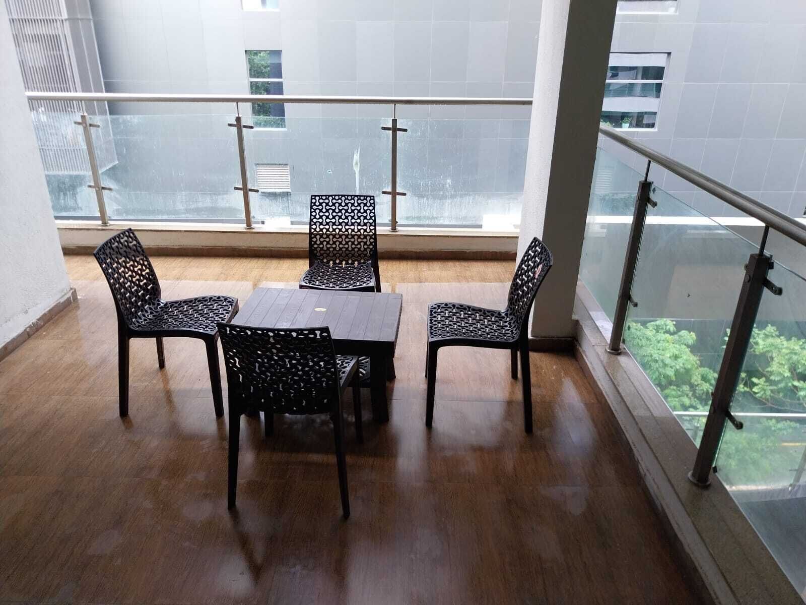 A balcony with a glass railing, a wooden floor, and a table with chairs.