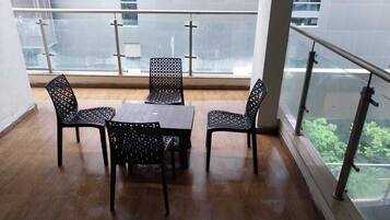 A balcony with a glass railing, a wooden floor, and a table with chairs.