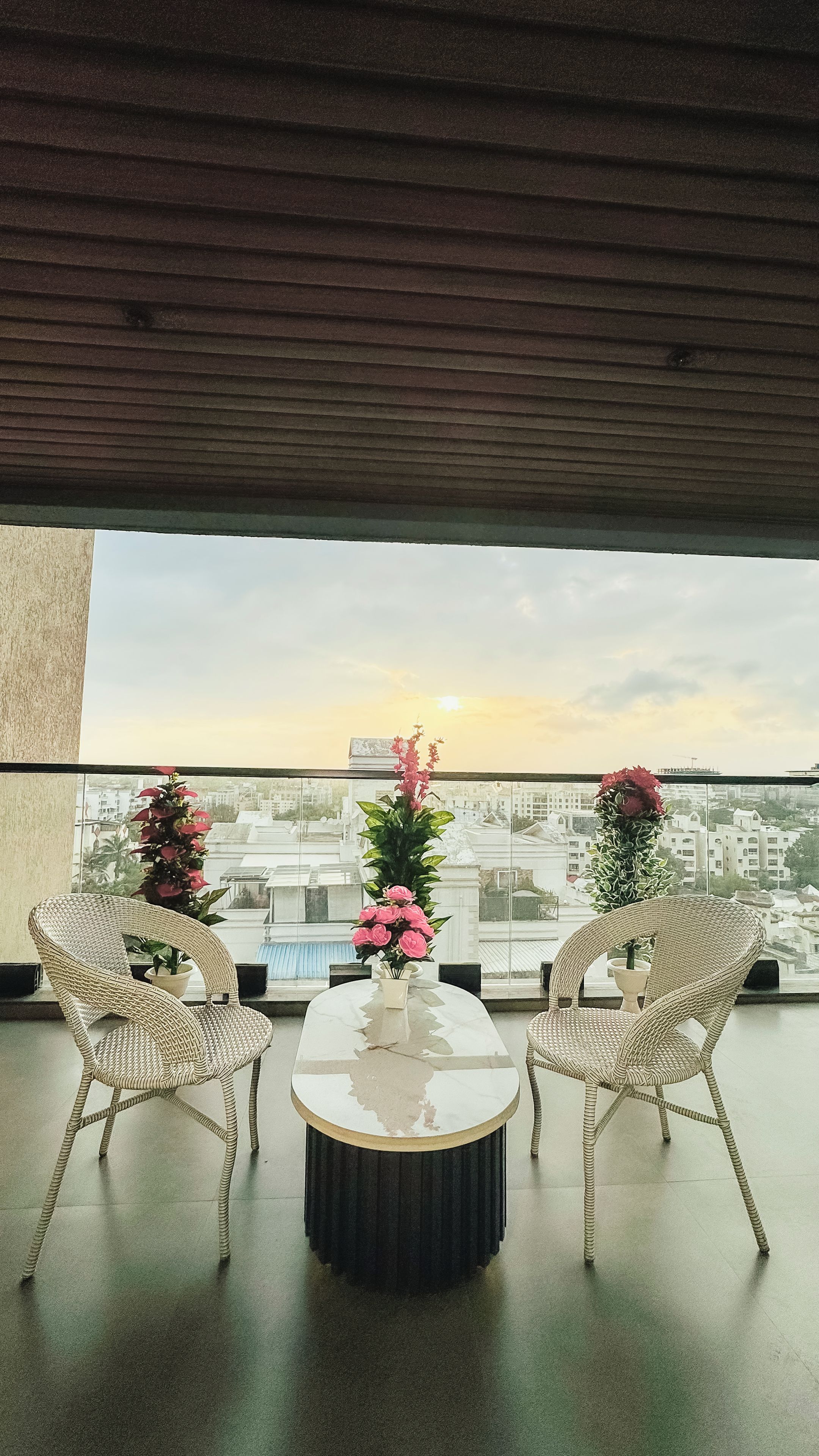 A balcony with two wicker chairs, a round table, and potted plants.
