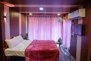 Una habitación con cama, escritorio, ventilador y aire acondicionado.