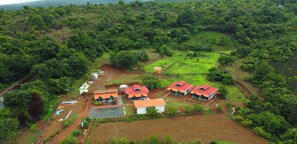 A rural property with multiple buildings, a paved driveway, and surrounding greenery. - Madhuban Nature Resort - Amboli (Amboli)