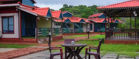 A row of cabins with red roofs and a covered seating area with a table and chairs.