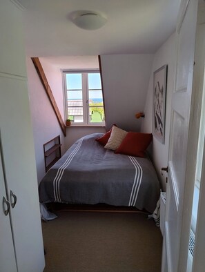 A bedroom with a bed, a window, a radiator, and a door. - Cosy 70s-style holiday apartment (Hollændergårde)