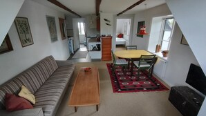 Una sala de estar acogedora con un sofá, una mesa de centro de madera y un comedor con mesa y sillas.