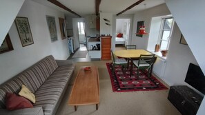 Ein gemütliches Wohnzimmer mit einer Couch, einem Holztisch und einem Essbereich mit Tisch und Stühlen.