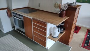 Una cocina compacta con estufa integrada, cafetera y un mueble con cajones.