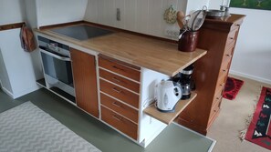 Eine kompakte Küche mit Einbauherd, Kaffeemaschine und einem Schrank mit Schubladen.