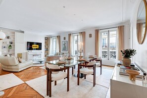 Ein geräumiges Wohnzimmer mit Essbereich, einem Flachbildfernseher und einem Balkon mit Blick.