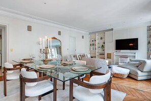 Ein stilvolles Wohnzimmer mit Glastisch, einer Couch, einem Fernseher und einem Klavier.