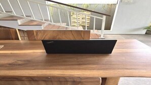 Ein Laptop steht auf einem Holztisch in einem Raum mit einer Treppe im Hintergrund.