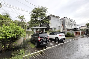 A residential area with two parked cars, a paved driveway, and a building with a modern design. - Twin Room Near Sanur Beach (Bali)