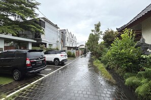 Een smalle straat met geparkeerde auto's en een gebouw in traditionele stijl.