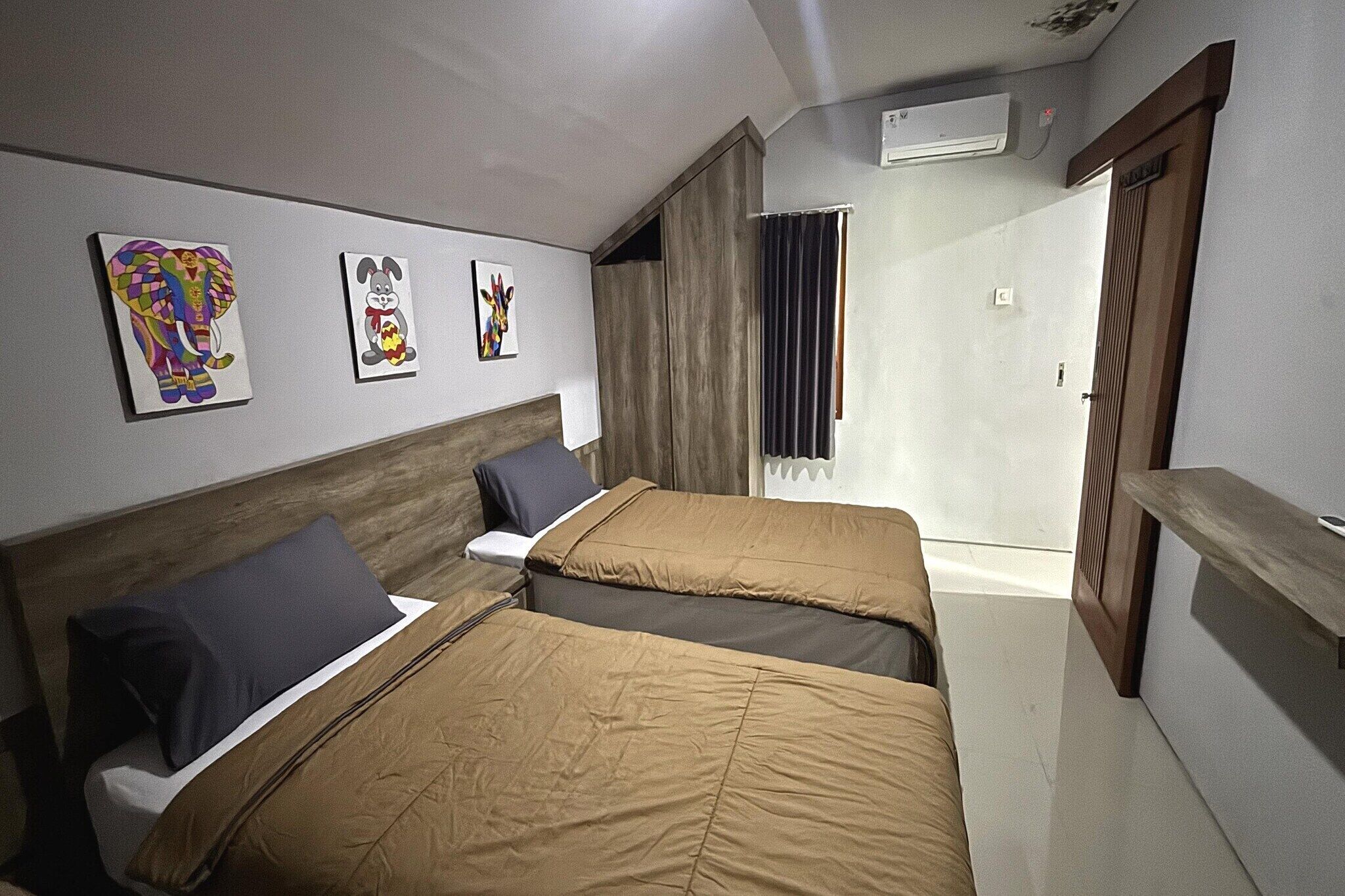 Une chambre d’hôtel avec deux lits, une tête de lit en bois, une petite table et un espace douche.