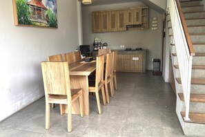 Ein Essbereich mit Holztisch und -stühlen, eine Küche mit Holzschränken und eine Treppe mit Holzboden.