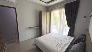 Un dormitori amb llit, armari, finestra amb cortines i porta.