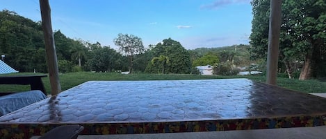 A covered outdoor seating area with a view of a lush green landscape.
