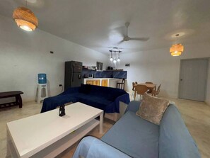 A living room with a sofa, a coffee table, a dining table with chairs, a kitchen area with a refrigerator, and a ceiling fan. - Tranquil Villa Retreat in Las Terrenas - Pet-Friendly Haven (Las Terrenas)