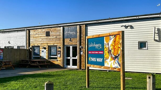 Un edificio con un cartel que dice 'fish&chips' y servicio de entrega.