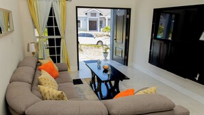 A living room with a sofa, a table, and a TV. - Beyond Escape-Solar-Powered-3BDRM-Near Ocho Rios (Boscobel)