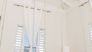 A room with a high ceiling, white walls, and a bed with a patterned pillow. - Beyond Escape-Solar-Powered-3BDRM-Near Ocho Rios (Boscobel)
