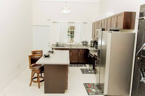 A modern kitchen with a central island, stainless steel appliances, and wooden cabinetry. - Beyond Escape-2BR-Gated-15 Min to Ocho Rios (Boscobel)