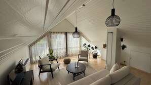 A spacious loft with a high ceiling, a sofa, a round coffee table, a TV, and a dining area. - Nordi Living Apartment—ideally located in the heart of Baden-Württemberg (Horb am Neckar)