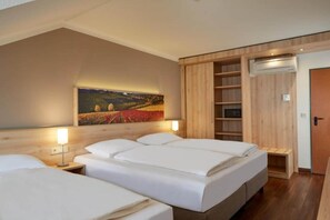 Habitación de hotel con tres camas, un cuadro en la pared, un armario de madera y un equipo de aire acondicionado.