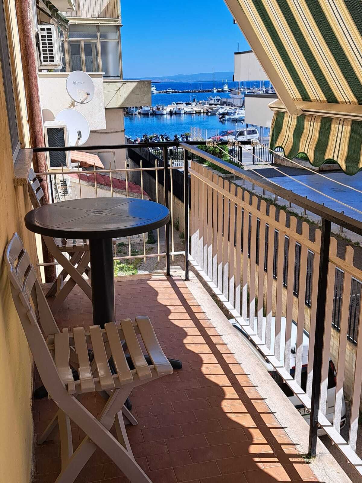 A balcony with a table and chairs, overlooking a marina with boats.