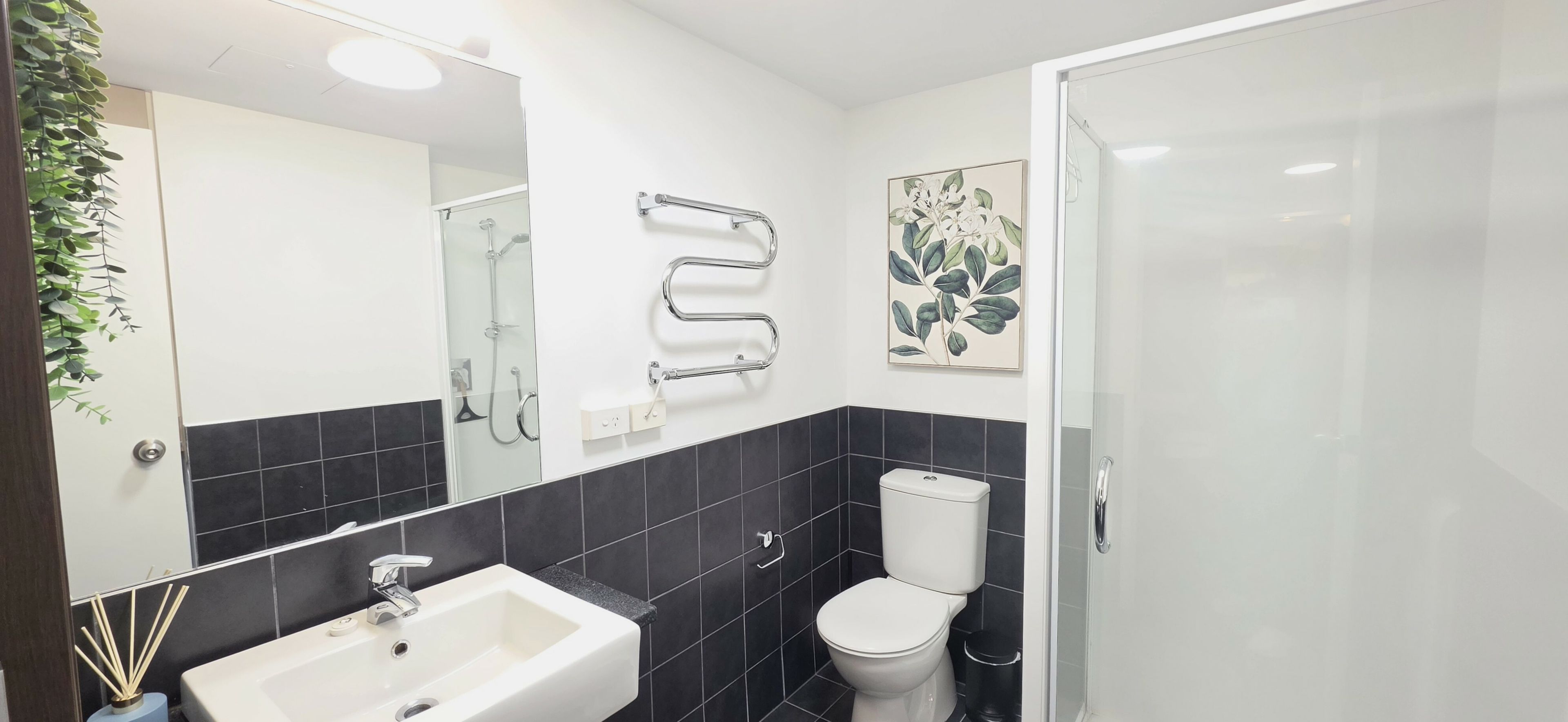 A modern bathroom with a white sink, a toilet, and a glass shower enclosure.