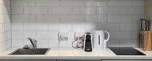 A kitchen with a stainless steel sink, a kettle, and a tablet on the counter. - Immaculate 2BDR Central City Chic Apartment (Auckland)